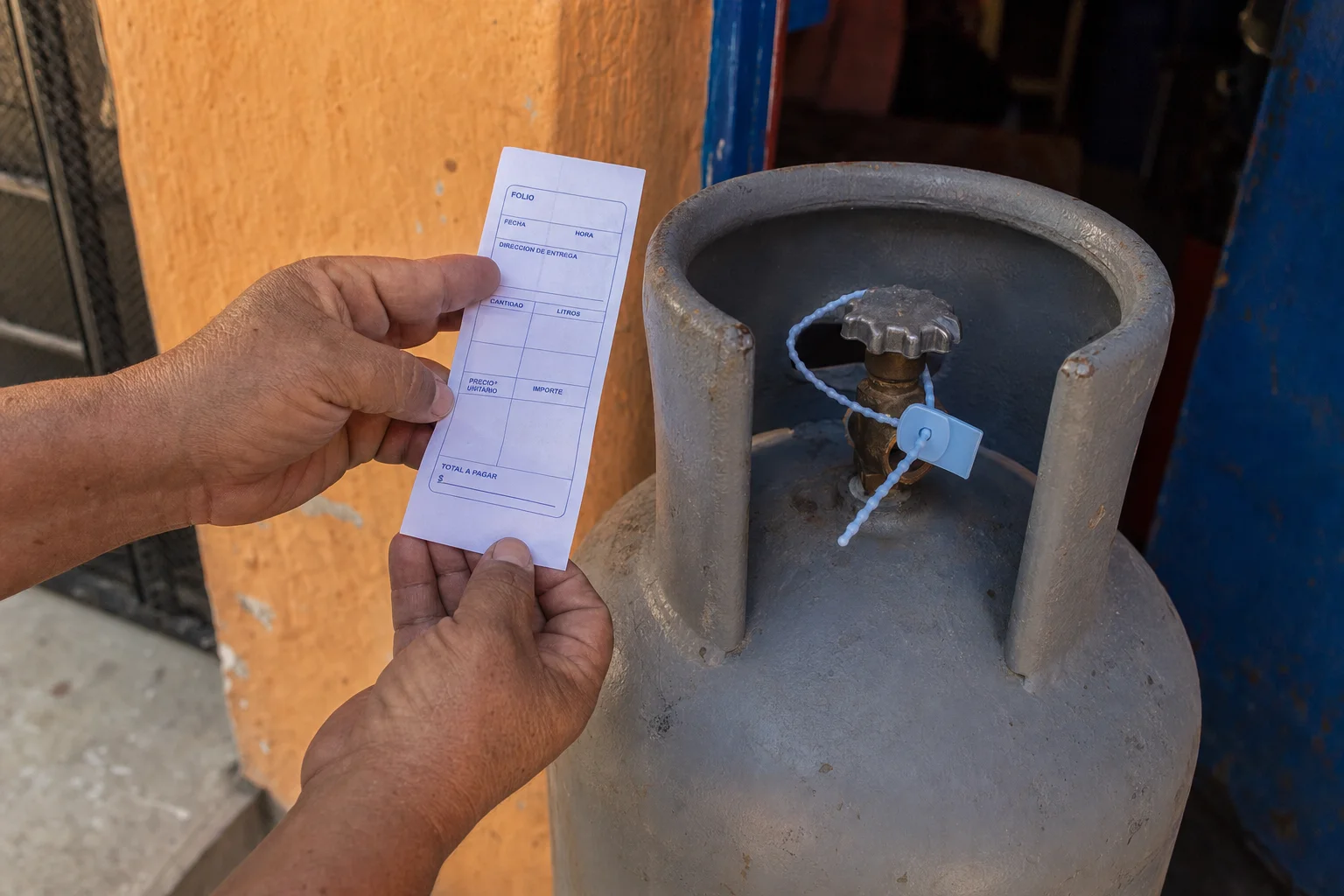 Manos sosteniendo un ticket impreso junto a un cilindro de gas sellado